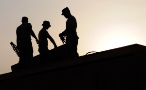 Silhouette of three workers wearing safety caps while working