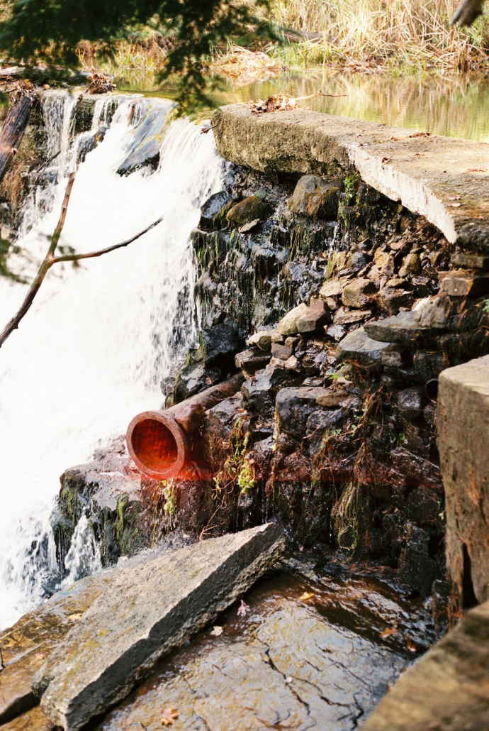 A fiberglass pipe opening into a large pond with sewer water. 